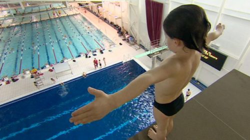 Child preparing for a high-dive into swimming pool
