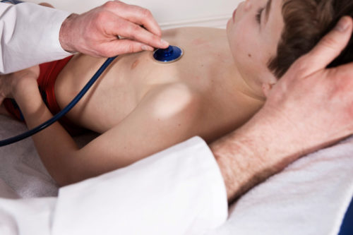 Doctor doing a good cardiac exam of a boy