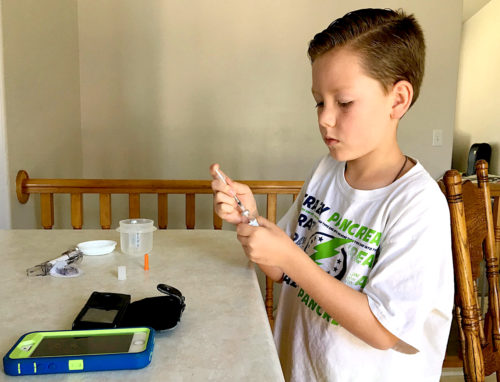 Boy with type 1 diabetes mixing insulin