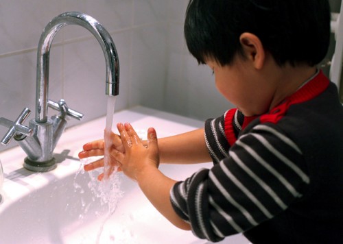young boy washing his hands