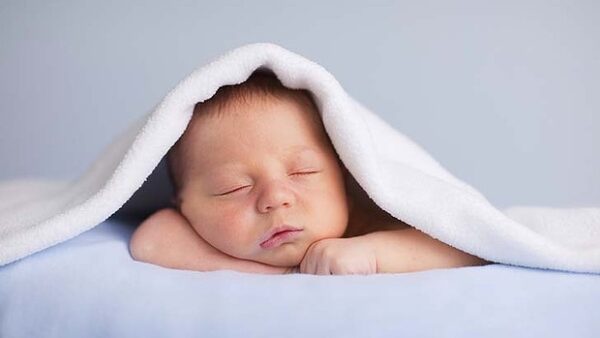Infant asleep on belly under blanket