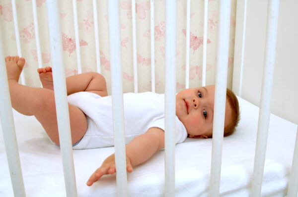 Infant, sleepless, on back in crib