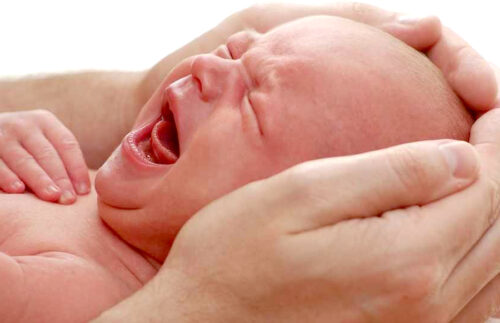 Father holding colicy infant in his hands